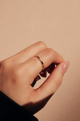 穿黑色皮衣的女人在左手中指被帶了精緻的金色鋯石細戒