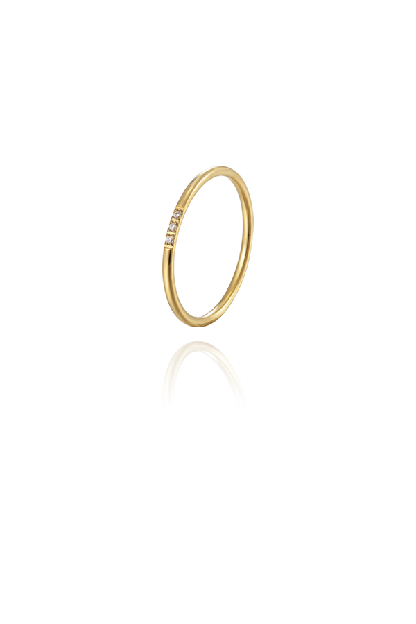 Slim gold ring with a delicate row of small diamonds, displayed on a reflective surface, showcasing its minimal and elegant design.