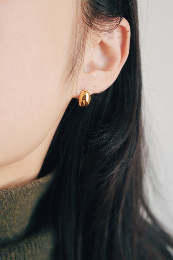 Asian woman in winter sweater wearing dainty gold studs