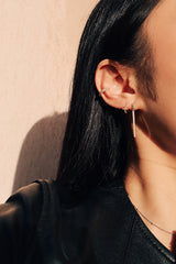 Female model stacking three types of earrings to create a playful look