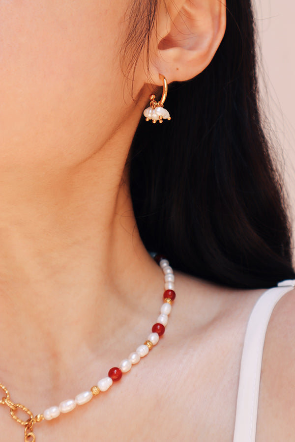 Asian girl wearing elegant freshwater pearl hoop earrings paired with a pearl and red bead choker necklace, highlighting the earrings delicate and sophisticated design.