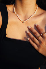 Woman in a black top wearing a freshwater pearl choker with a small 18k gold bead, showcasing the choker's delicate and luxurious design.