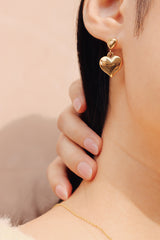 Asian girl pulling her hair back to reveal the duo heart shape gold earring on one side from shnco 