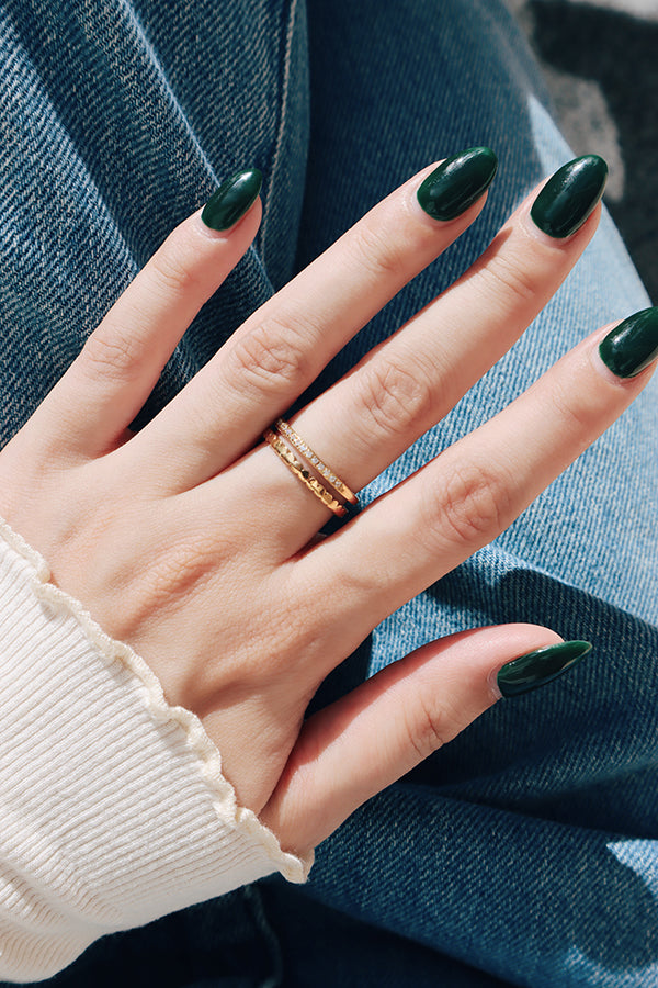 A hand wearing a gold stacking ring against casual jeans, highlighting a chic and effortless style.