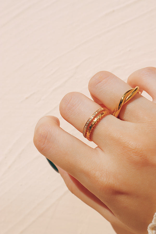 Hand wearing layered gold stacking rings in a minimalist style, showcasing elegant and delicate jewelry.