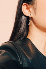 時尚模特兒站在陽光下右耳配戴了銀色抗敏防水的獨特造型設計師耳環