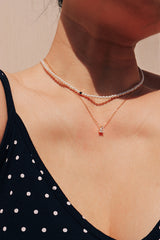 Elegant woman wearing Swarovski pearl choker layering with dainty shiny drop necklace