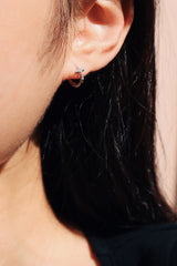 鏡頭近距離拍攝黑髮模特兒所配戴的純銀十字小圈圈耳環細節
