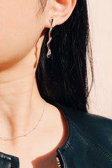Girl in black leather jacket showing her silver drop earrings under the sun