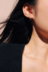Woman showing her half face with 925 silver huggie on her ear