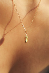 Detailed shot of a woman wearing a sterling silver 14K plated necklace with a peridot gemstone, emphasizing the necklaces refined design.