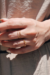 Close-up of a womans hand wearing a tarnish-free crossed 18K gold ring, capturing the rings elegant and stylish design.