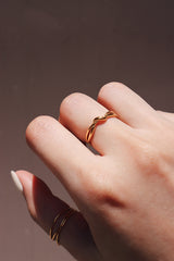 Close-up of a womans hand wearing a tarnish-free gold knot ring, capturing the ring's intricate and stylish design.