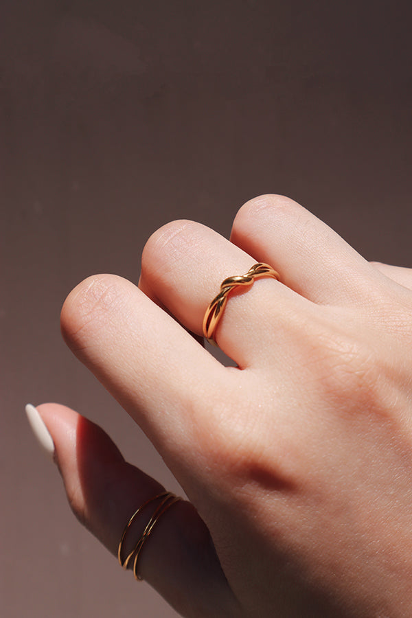 Close-up of a womans hand wearing a tarnish-free gold knot ring, capturing the ring's intricate and stylish design.