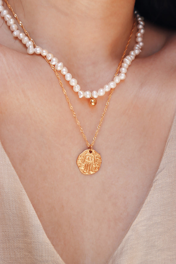 Asian girl wearing a layered look with a water-resistant elegant pearl choker and a gold medallion necklace, showcasing the choker's timeless style and versatility.