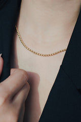 Close-up of a woman wearing an 18K gold-plated rope chain necklace, styled with a black blazer, emphasizing the necklace's polished and refined look.