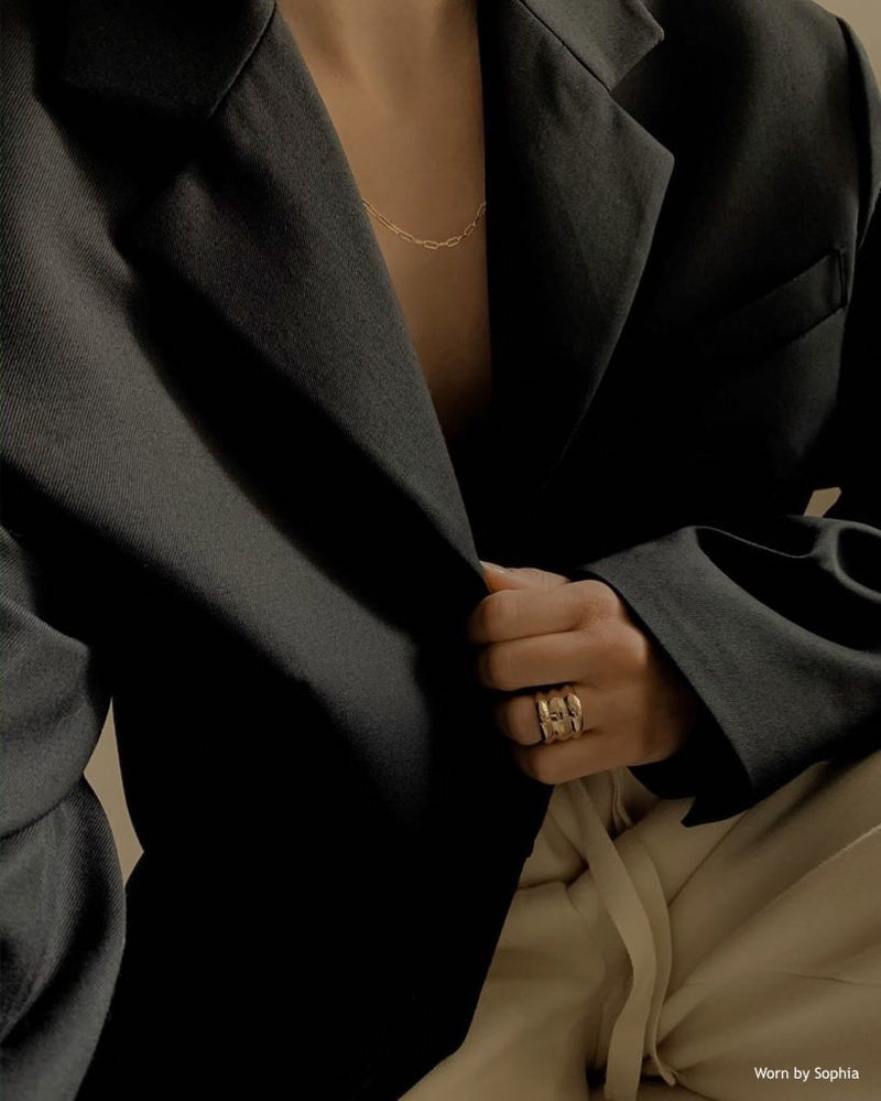 Girl with suit jacket wearing a gold chunky on her ring finger