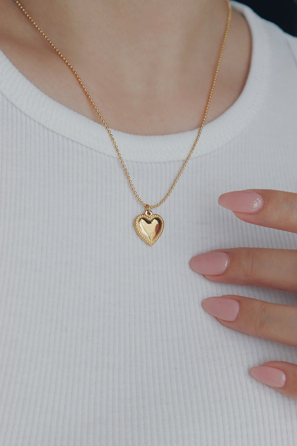 Gold heart beads necklace from SH & Co., with small heart-shaped pendants distributed along a slender gold chain, radiating subtle elegance.