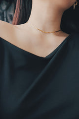 Elegant hypoallergenic gold choker worn by a woman, featuring a smooth and minimalistic design, complementing a sleek black top.