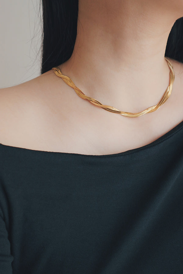 Close-up of a hypoallergenic gold snake necklace draped gracefully around a woman’s neck, highlighting its sleek and smooth texture.