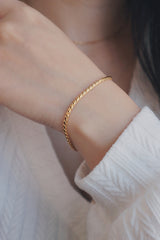 A close-up view of a wrist adorned with a hypoallergenic rope chain bracelet, styled with a white textured top, highlighting the bracelets sleek and elegant design.