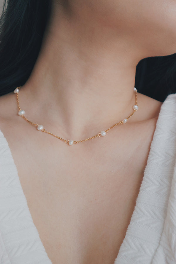 Luxurious necklace combining a textured gold pendant and freshwater pearls on a multi-strand chain, offering a timeless piece for any collection.