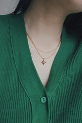 Close-up of a woman showcasing various SH & Co. gold necklaces layered together, offering stylish layering ideas.