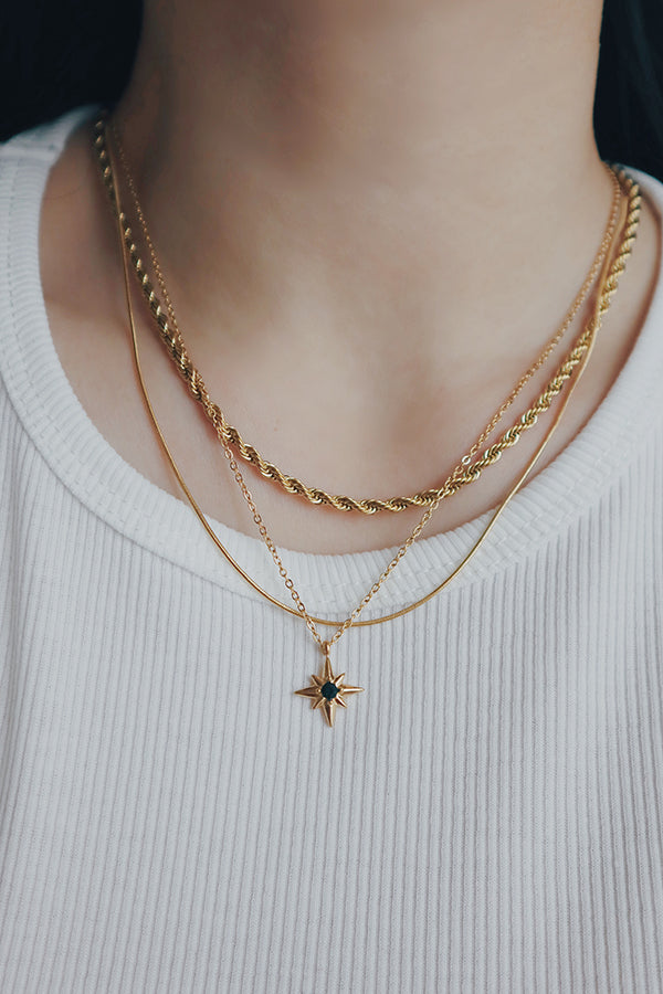 SH & Co. Essie necklace featuring a green cubic zirconia star pendant, worn with a white top.