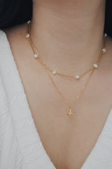 A hypoallergenic, gold-plated necklace showcasing a layered design with a central sunburst pendant and intermittent freshwater pearls on a fine chain, ideal for sensitive skin.