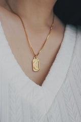 A woman wearing the SH & Co. Phoebe Luna necklace, featuring a gold-plated pendant with a crescent moon and sunburst design, styled with a white textured V-neck top for a stylish finish.