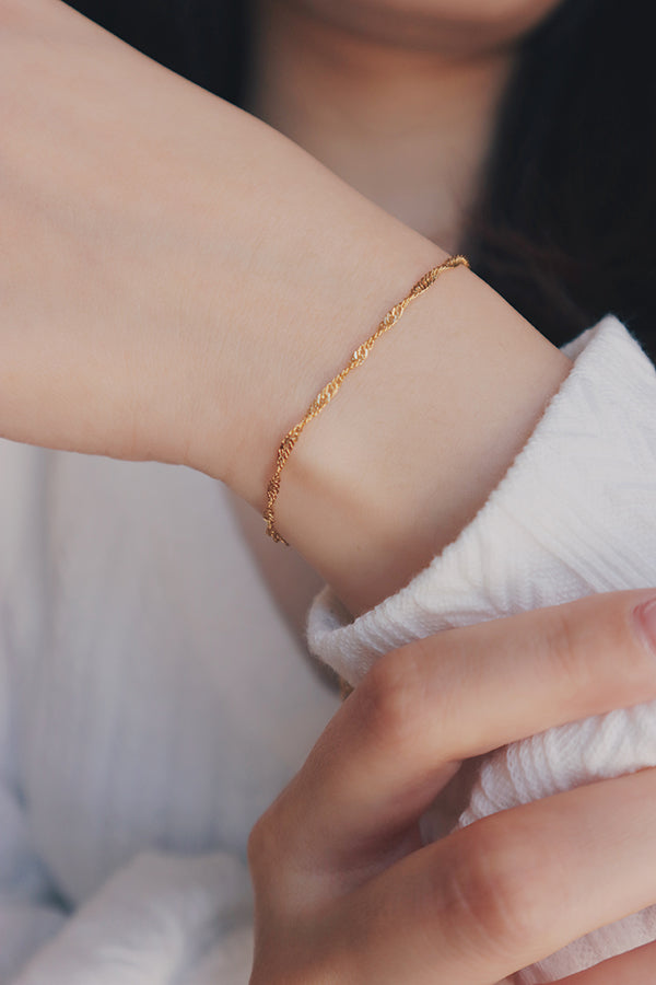 SH & Co. branded Singapore chain bracelet in gold, worn on the wrist with a focus on its durable design and hypoallergenic material.