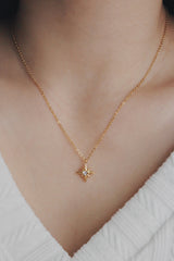 SH & Co. star necklace with a white cubic zirconia center, worn with a white knit top.