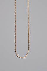 Close-up image of a minimalist stainless steel rope chain necklace displayed against a neutral background, showcasing its intricate twisting design.