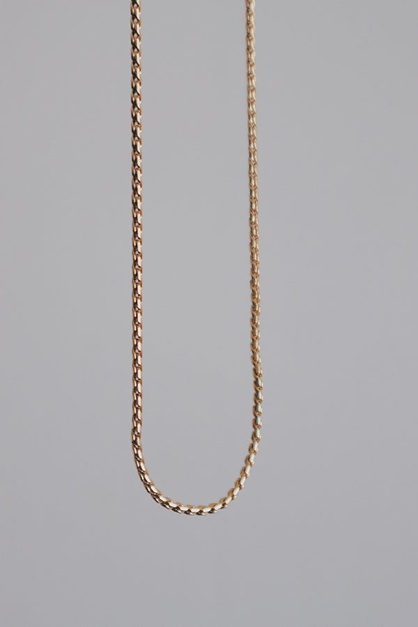 Close-up image of a minimalist stainless steel rope chain necklace displayed against a neutral background, showcasing its intricate twisting design.