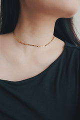 Woman wearing a stainless steel gold-toned choker with a unique geometric pattern, paired with a dark green blouse.