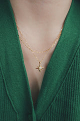 Tarnish-free star necklace with a pearl center, worn with a white top and layered with a pearl chain.