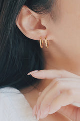 model wearing 2 gold hoop earrings